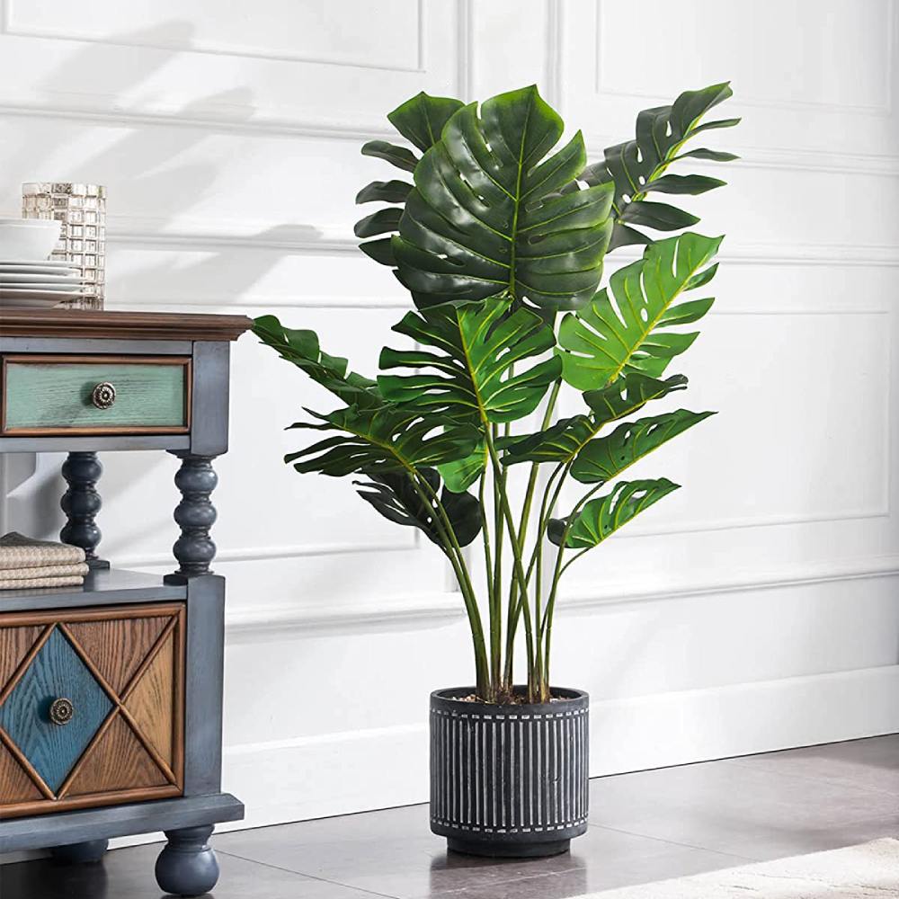An artificial monstera in a black nursery pot